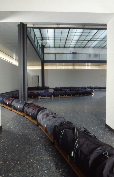 Aristocrat (1991) gallery installation. Large holdall bags (polyester/nylon) teak veneered chipboard, furniture latches, furniture castors (installation view, Mannheimer Kunstverein, Germany)